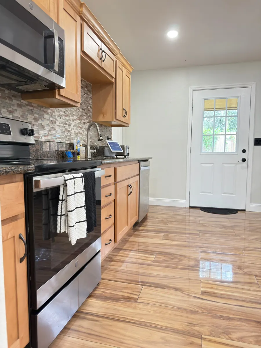Clean kitchen with wood cabinets, stainless steel appliances and shiny floor after a residential cleaning by AD Cleaning Orlando